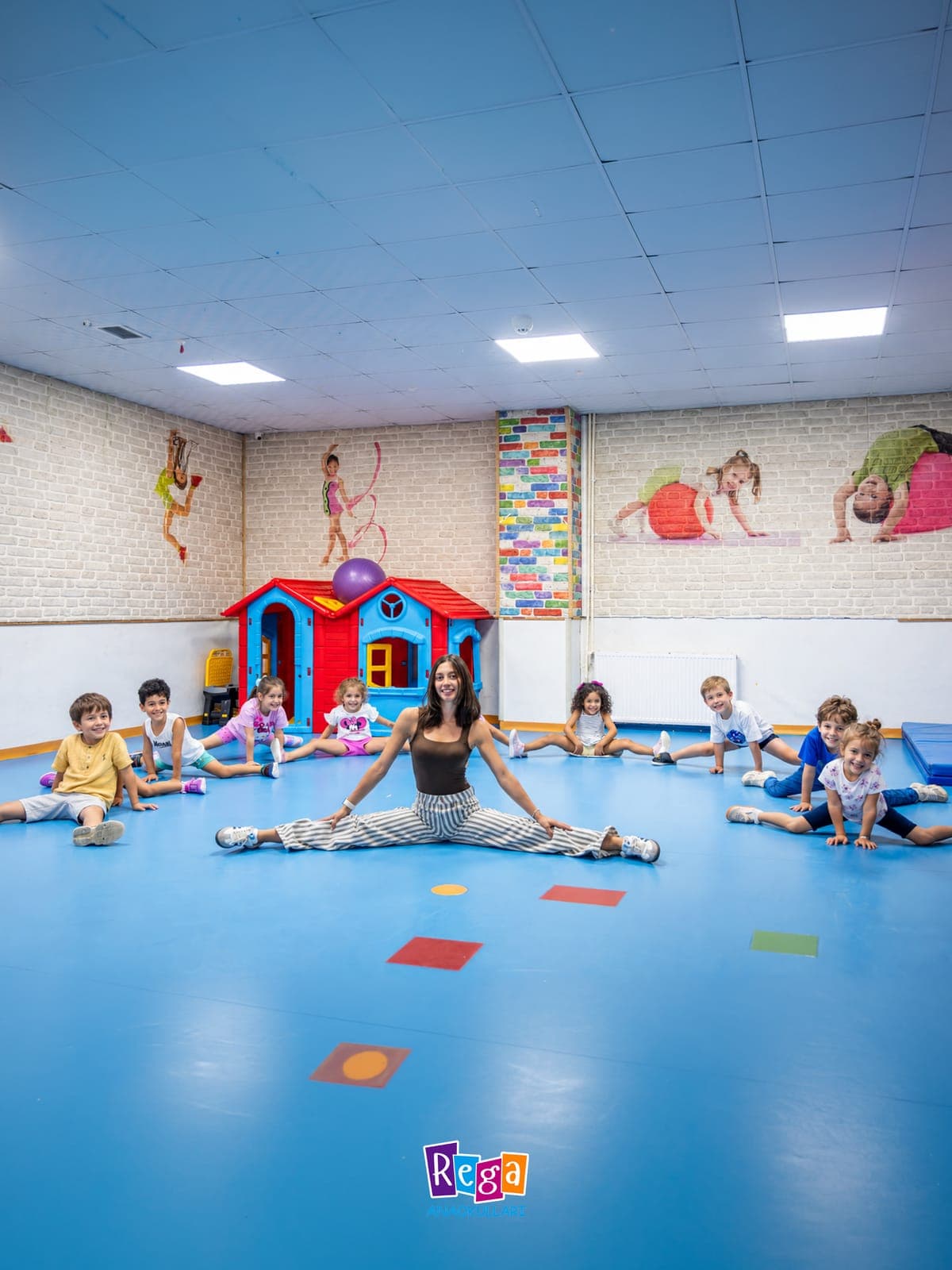 Spor salonunda öğretmeniyle birlikte bacaklarını açarak esneyen çocuklar