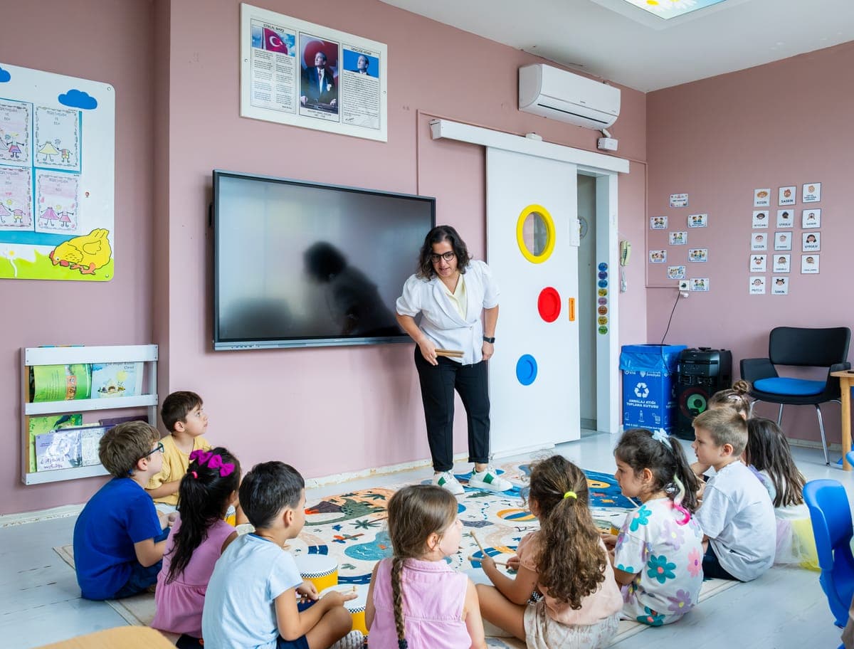 Sınıfta yerde oturan çocuklara ders anlatan öğretmen